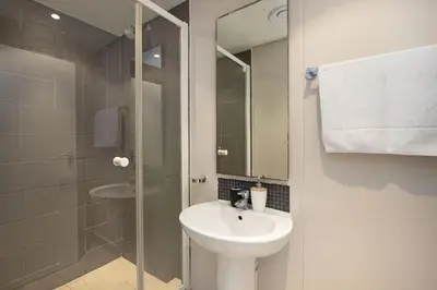 a white bathroom with a sink and a shower at Portico 405 in Bloubergstrand