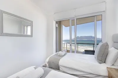 a bedroom with a bed and a view of the ocean at Portico 704 in Bloubergstrand
