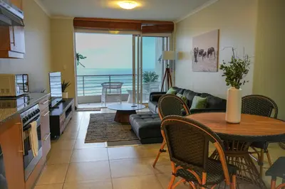 a kitchen and living room with a table and a couch at Portico 1002 in Cape Town