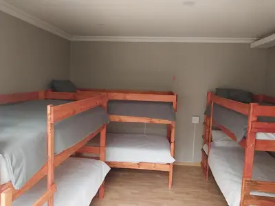 a room with three bunk beds in it at Serenity Shores Backpackers in Cape Town