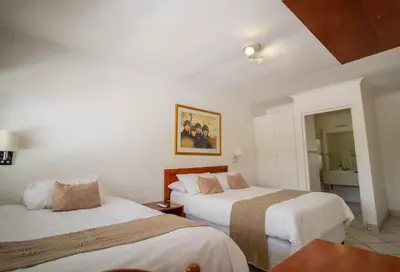 a hotel room with two beds and a mirror at Broadway Boston in Cape Town