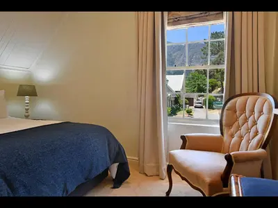 a bedroom with a bed and a chair and a window at Sunflower Villa in Franschhoek in Franschhoek
