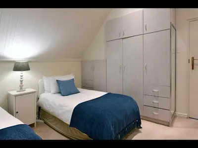 a bedroom with a bed with a blue blanket and cabinets at Sunflower Villa in Franschhoek in Franschhoek