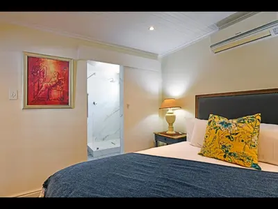a bedroom with a bed with a blue blanket and a window at Sunflower Villa in Franschhoek in Franschhoek