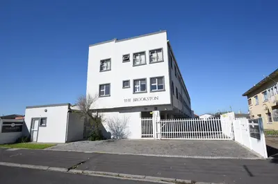 a white building with a white fence in front of it at The Brookston in Cape Town