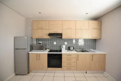 a kitchen with wooden cabinets and a stainless steel refrigerator at The Brookston in Cape Town