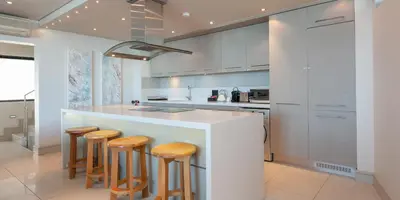a kitchen with a white counter and stools at Harbour House Hotel - Le Paradis Apartments in Hermanus