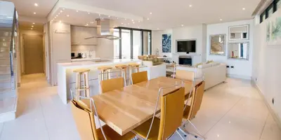 a kitchen and dining room with a wooden table and chairs at Harbour House Hotel - Le Paradis Apartments in Hermanus