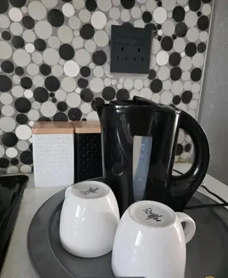 a black coffee pot and two white cups on a tray at Elite Escape in Cape Town