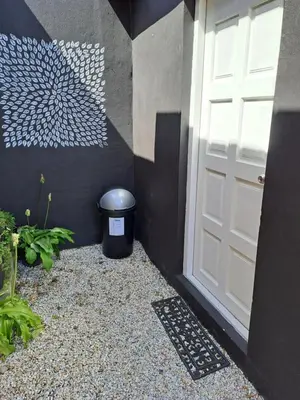 a white door and a trash can next to a building at Milky Way in Hermanus