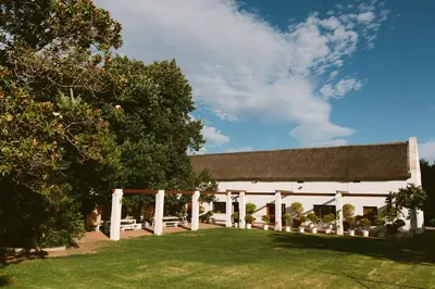a white barn with a porch and a yard at Leipzig Country House & Winery in Nuy