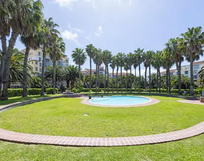 a park with a swimming pool and palm trees at Capri On Lake 101 The Island Club in Cape Town