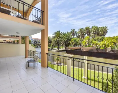 a balcony with a view of a river and palm trees at Capri On Lake 101 The Island Club in Cape Town