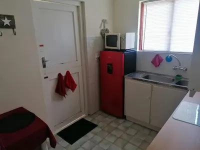a small kitchen with a red refrigerator and a microwave at HARTSRUS in Kleinmond