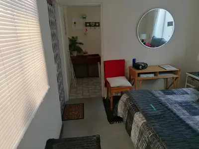 a bedroom with a bed and a chair and a mirror at HARTSRUS in Kleinmond