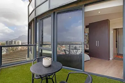 a room with a table and chairs on a balcony at Grand Penthouse / Backup Power / Stunning in Cape Town