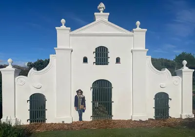 a person standing in front of a white building at Franschhoek Mountain Views in Franschhoek