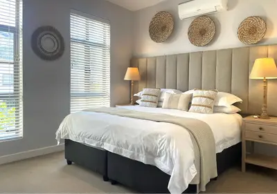 a bedroom with a large bed and two windows at Franschhoek Mountain Views in Franschhoek