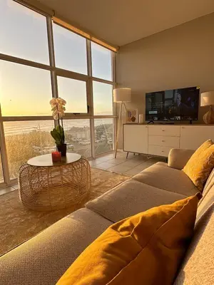 a living room with a couch and a tv at Charming beachfront Strand apartment in Cape Town