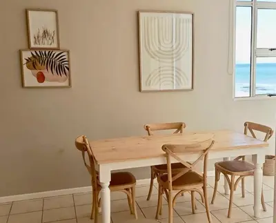 a dining room with a wooden table and chairs at Charming beachfront Strand apartment in Cape Town