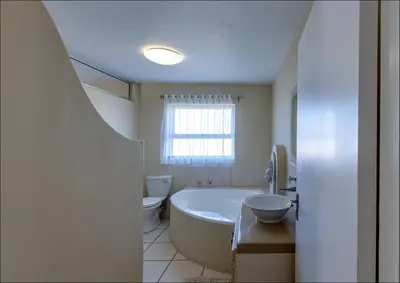 a bathroom with a tub and a toilet and a sink at Sunset Terrace in Hermanus