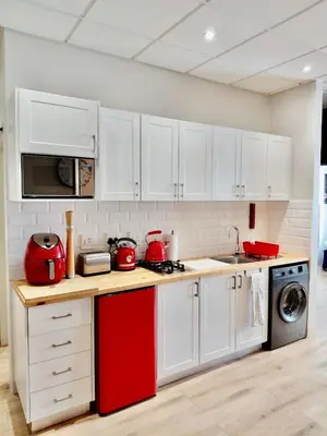 a kitchen with white cabinets and red appliances at Pepper Korrel - Paarl - Self Catering Apartment in Paarl