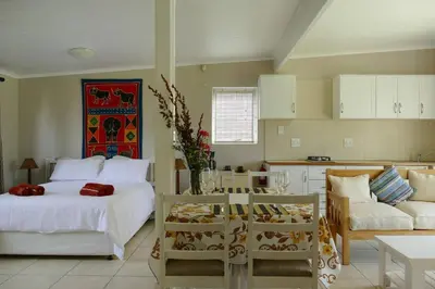 a bedroom with a bed and a couch and a kitchen at Cuckoo's Corner in Bettyʼs Bay