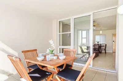 a dining room with a wooden table and chairs at Lagoon Beach 29A in Cape Town