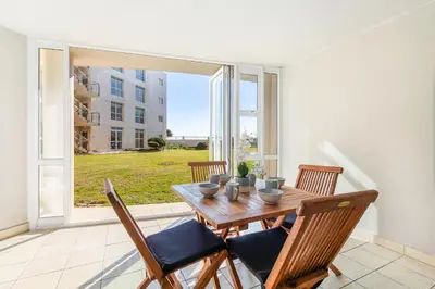 a dining room with a table and chairs and a large window at Lagoon Beach 29A in Cape Town