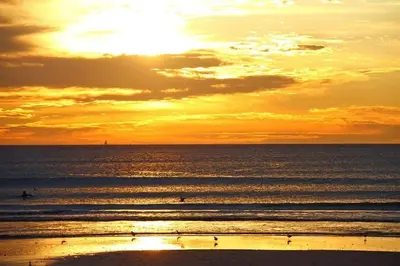 a sunset over the ocean with people surfing at Lagoon Beach 29A in Cape Town