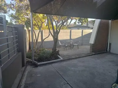 a patio with a table and chairs and a tree at Two bedroom flatlet in Panorama in Cape Town