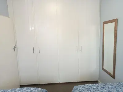 a bedroom with white cabinets and a bed at Culemborg Court in Cape Town