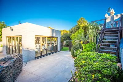 a house with glass doors and a staircase in a yard at Villa Luisa: Sun-filled hidden gem with Pool. in Cape Town