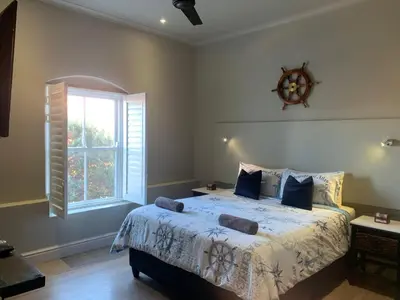 a bedroom with a large bed and a window at Hermanus Waterfront Apartment 12 in Hermanus