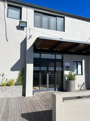 a building with glass doors and a bench in front of it at Hermanus Waterfront Apartment 12 in Hermanus