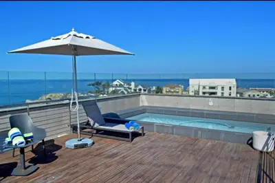 a swimming pool with an umbrella and two chairs and an umbrella at Hermanus Waterfront Apartment 12 in Hermanus