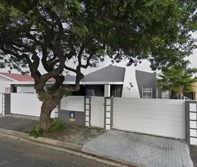 a white fence and a tree in front of a house at McSheyson Apartment - Deluxe in Cape Town