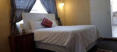 a bedroom with a white bed with a window at McSheyson Apartment - Deluxe in Cape Town
