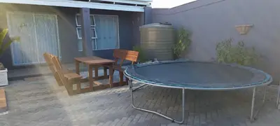 a patio with a table and chairs and a barrel at McSheyson Apartment - Deluxe in Cape Town