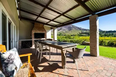a patio with a table and chairs and a fireplace at Dorpsig Cottage in Paarl