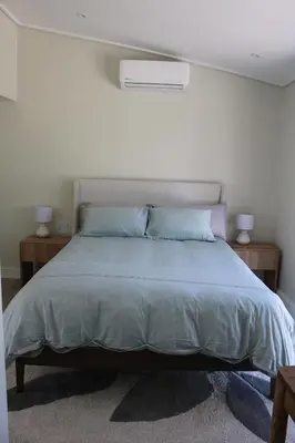 a bedroom with a bed with two night stands and two lamps at Digital Nomad's Nest, Somerset West in Cape Town