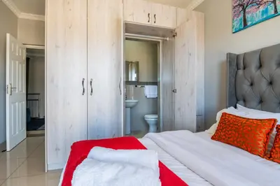 a bedroom with a bed with a red blanket on it at Enclaves Villa in Cape Town