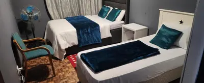 a small bedroom with two beds and a fan at Excel accommodation in Cape Town