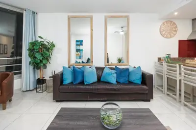 a living room with a brown couch with blue pillows at Seaside Sunsets in Strand