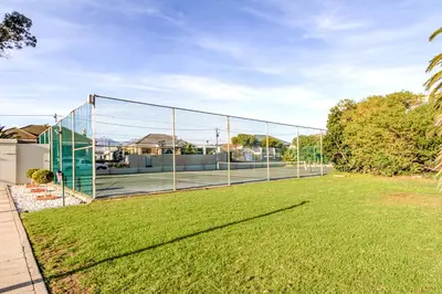 a tennis court with a net in a yard at Seaside Sunsets in Strand