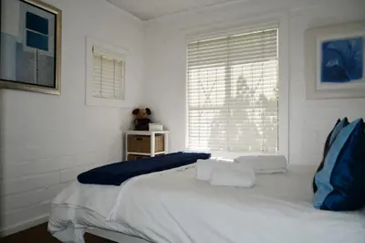 a white bedroom with a large bed and a window at Bradclin @ York in Cape Town