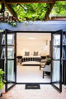 an open glass door leading to a patio with a couch at Paarl Hideaway in Paarl