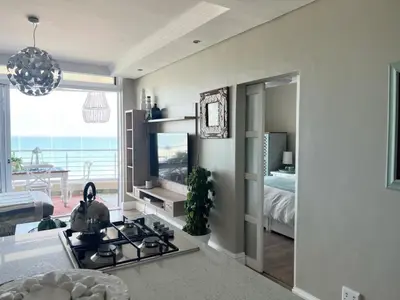 a kitchen with a stove and a living room with a bed at Portico 705 in Cape Town