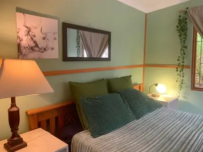 a bedroom with a bed and a lamp and a mirror at The Farmhouse Palm Tree Cabin in Stellenbosch