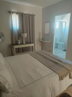 a bedroom with a large bed and a bathroom at Sophia’s Cottage in Cape Town